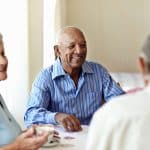 Nursing home residents sitting at a table smiling.