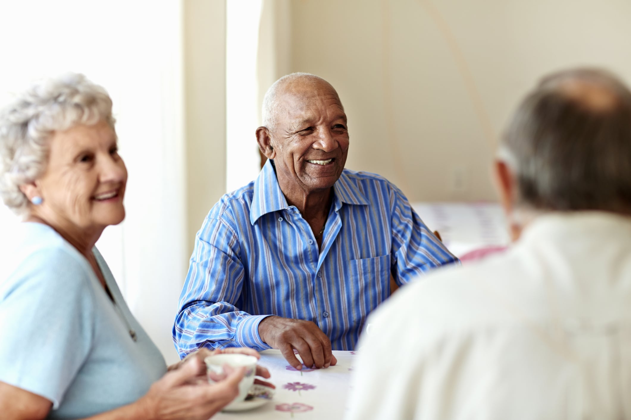 Nursing home residents sitting at a table smiling.