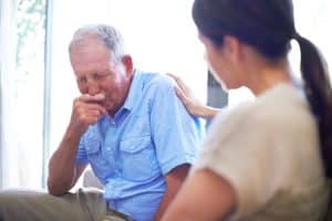 An elderly man crying to his daughter after suffering elder abuse.