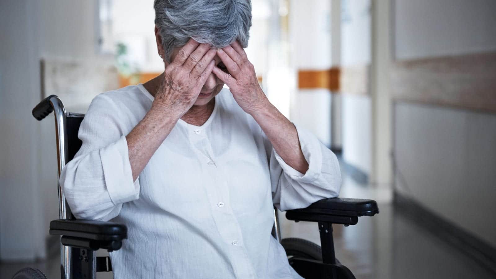 Shot of a senior woman in a wheelchair sitting with her hands over her eyes