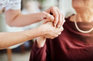 older woman holding hands with younger female nurse