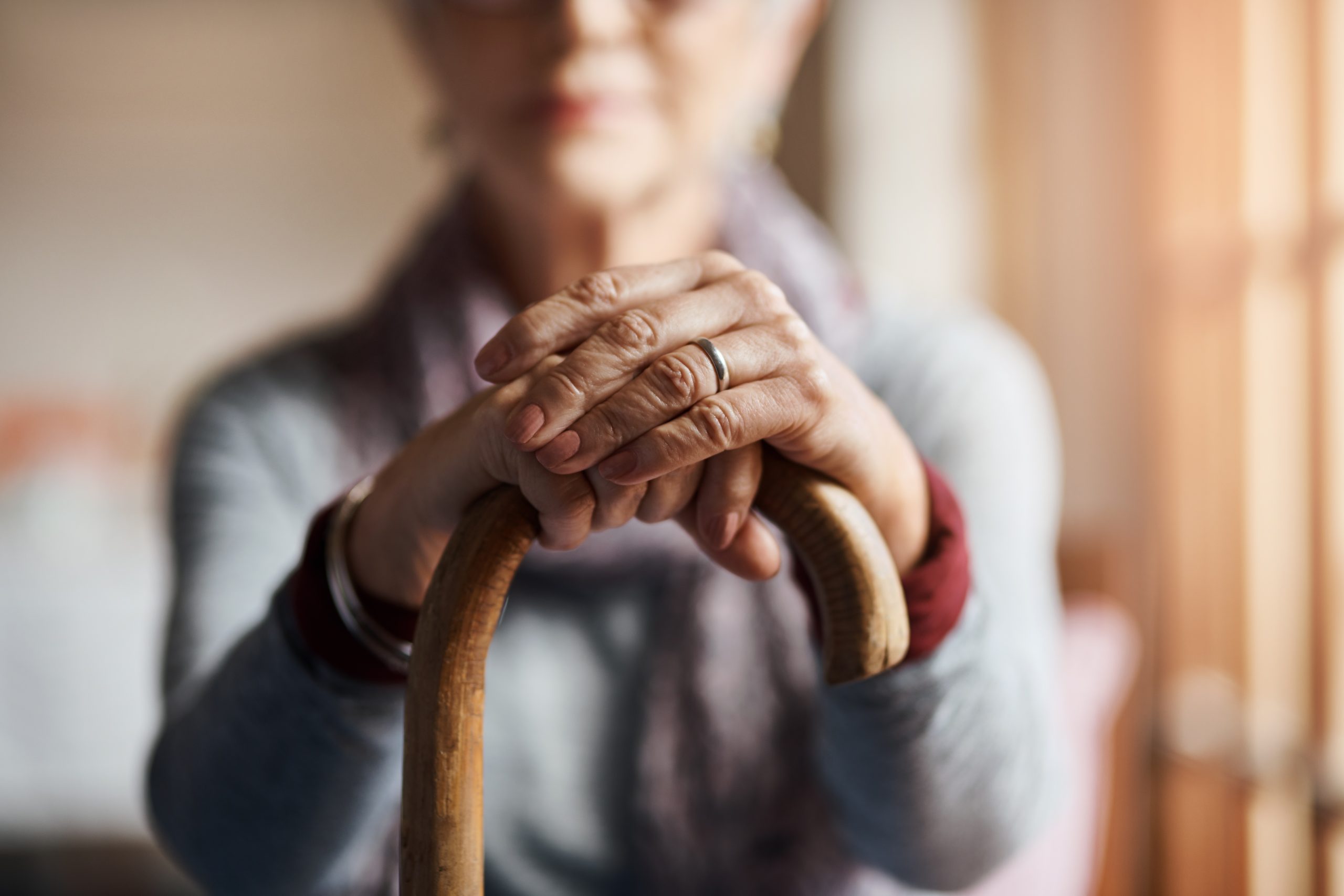 older woman sitting in chair holding cane