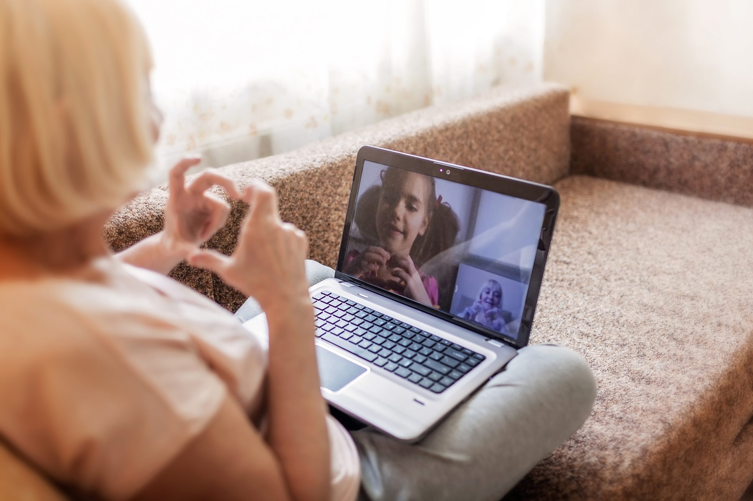 Cute girl talking with her grandmother within video chat on laptop, life in quarantine time