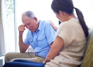 A woman comforting her elderly father who suffered nursing home neglect.