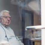 An elderly man sitting alone in his nursing home room.