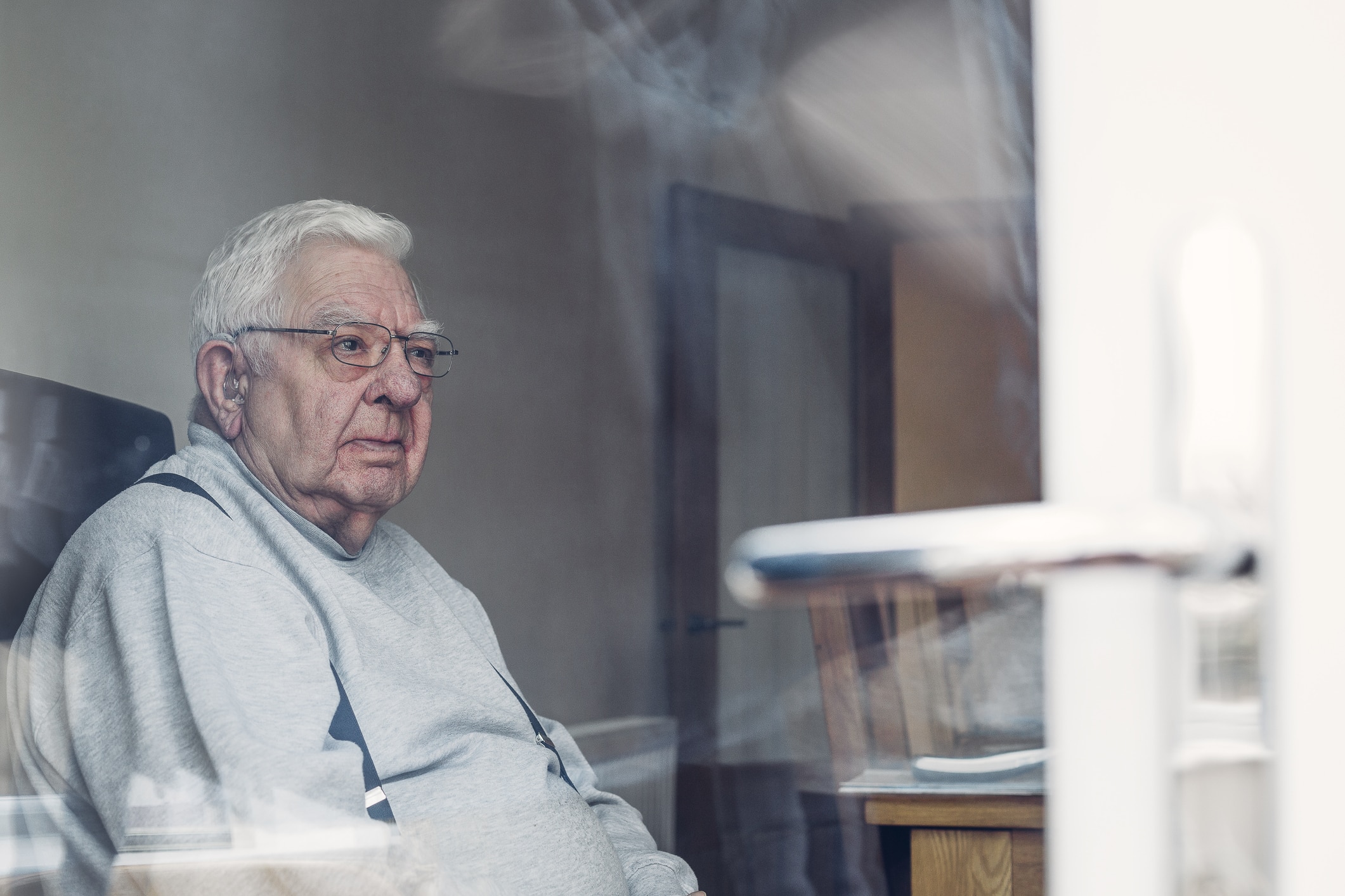 An elderly man sitting alone in his nursing home room.