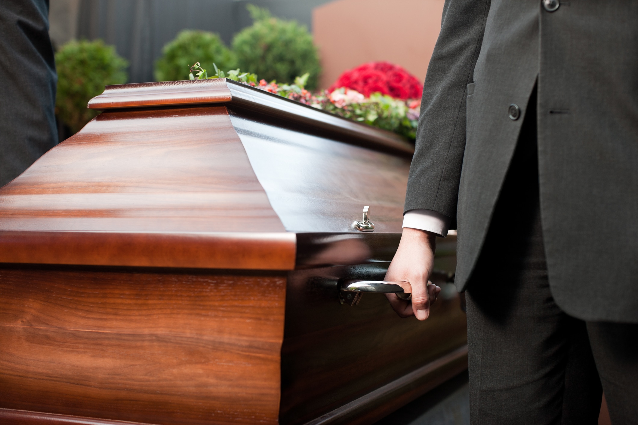 A man holding the handle on a casket.